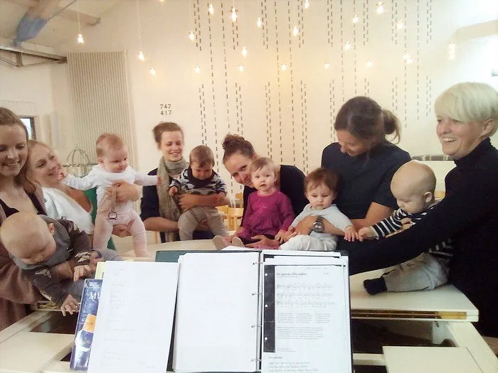Mehrere Erwachsene und Babys bei einem Gruppentreffen.